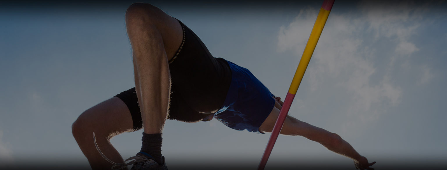 Track and field athlete executing a high jump over a yellow and red crossbar against a cloudy sky background.