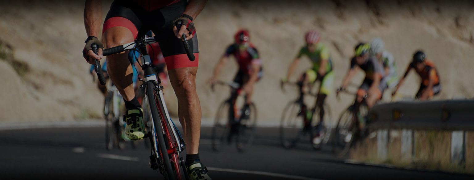 Lead cyclist in custom cycling bib and jersey riding in a competitive road cycling peloton.