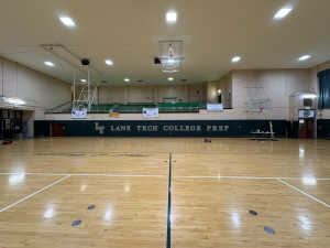 Custom green protective wall padding with gold Lane Tech College Prep lettering installed along a basketball court wall.