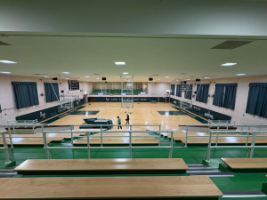 High-angle view of Lane Tech high school gymnasium featuring green wall safety padding around the basketball court perimeter.